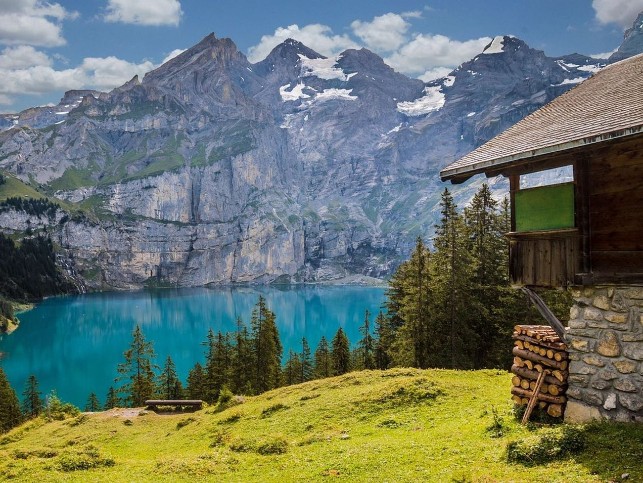 Una baita nel bosco riflessa nella superficie gelida di un lago di montagna